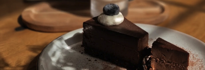 Stück Schokoladentkuchen mit Blaubeere und Sahnehaube, serviert auf einem weißen Teller im Neo Café Deli Ramstein