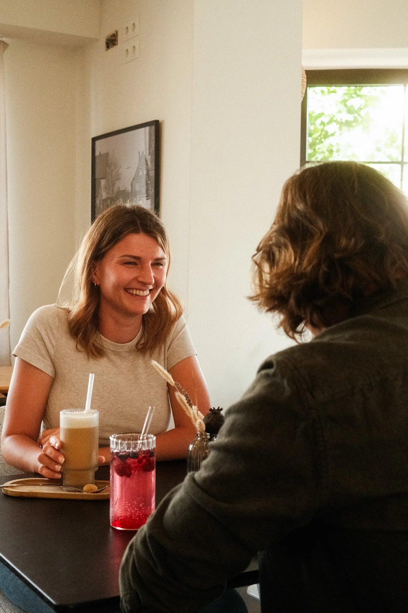 Zwei Gäste genießen ihre Drinks und lachen gemeinsam im Neo Café Deli in Ramstein – entspannte Stimmung bei Latte Macchiatto und einer Beeren Limo