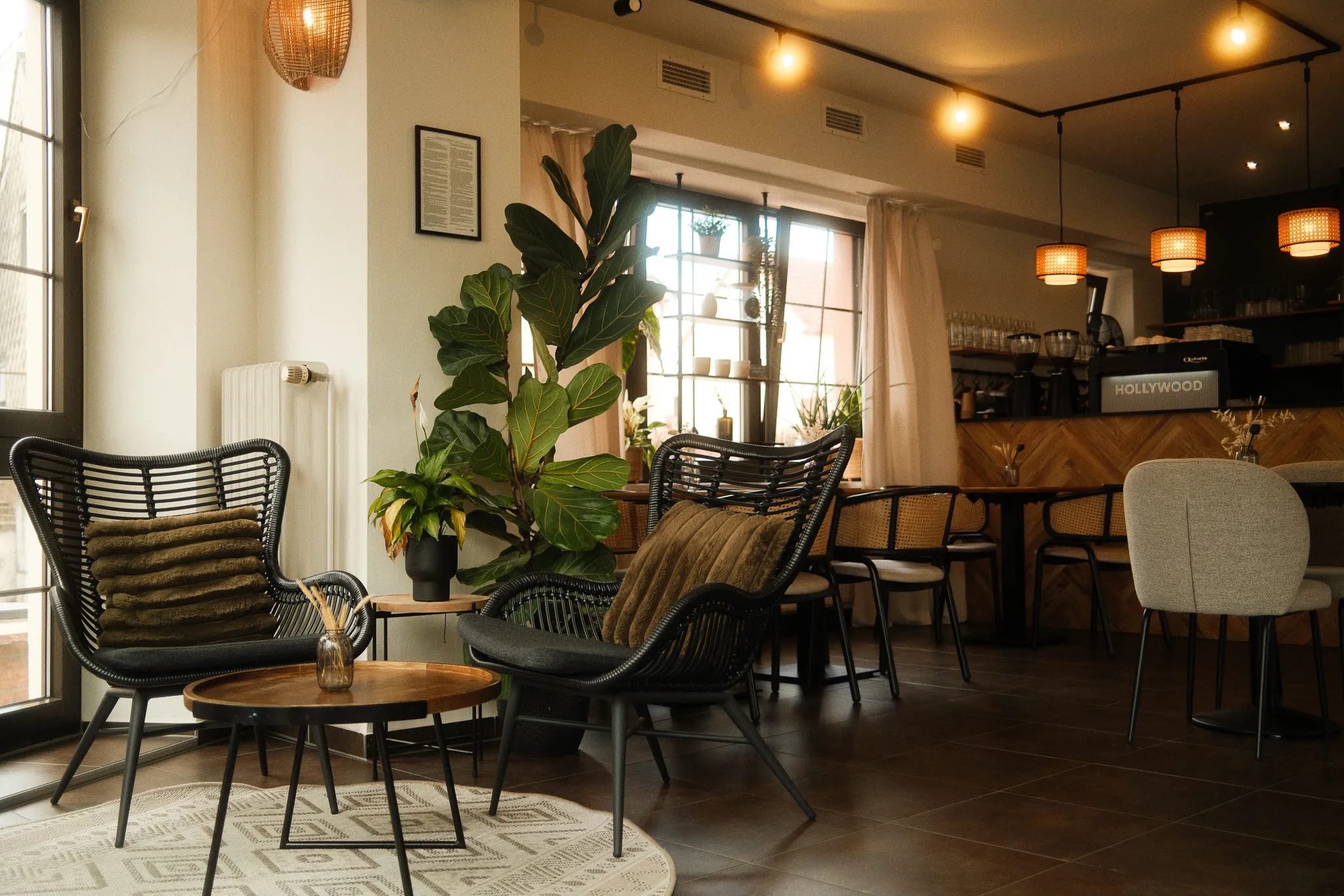 Gemütliche Lounge-Ecke im Neo Café Deli in Ramstein mit Rattansesseln, Zimmerpflanzen und natürlichem Lichteinfall – ideal zum Entspannen oder Arbeiten